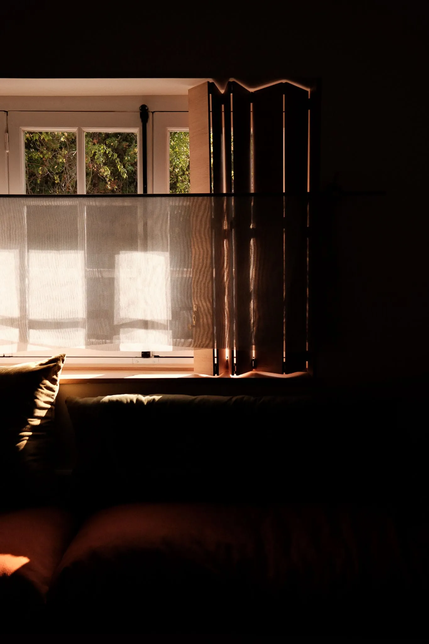 Chambre baignée de lumière derrière un paravent en bois, à La Maison Plume