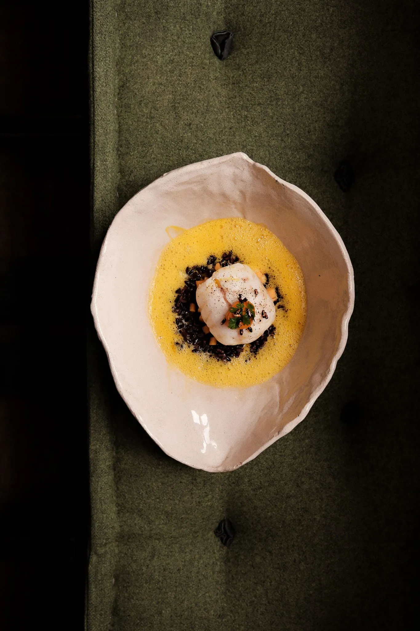 Dessert dans une assiette de grès posée sur une banquette de velours vert