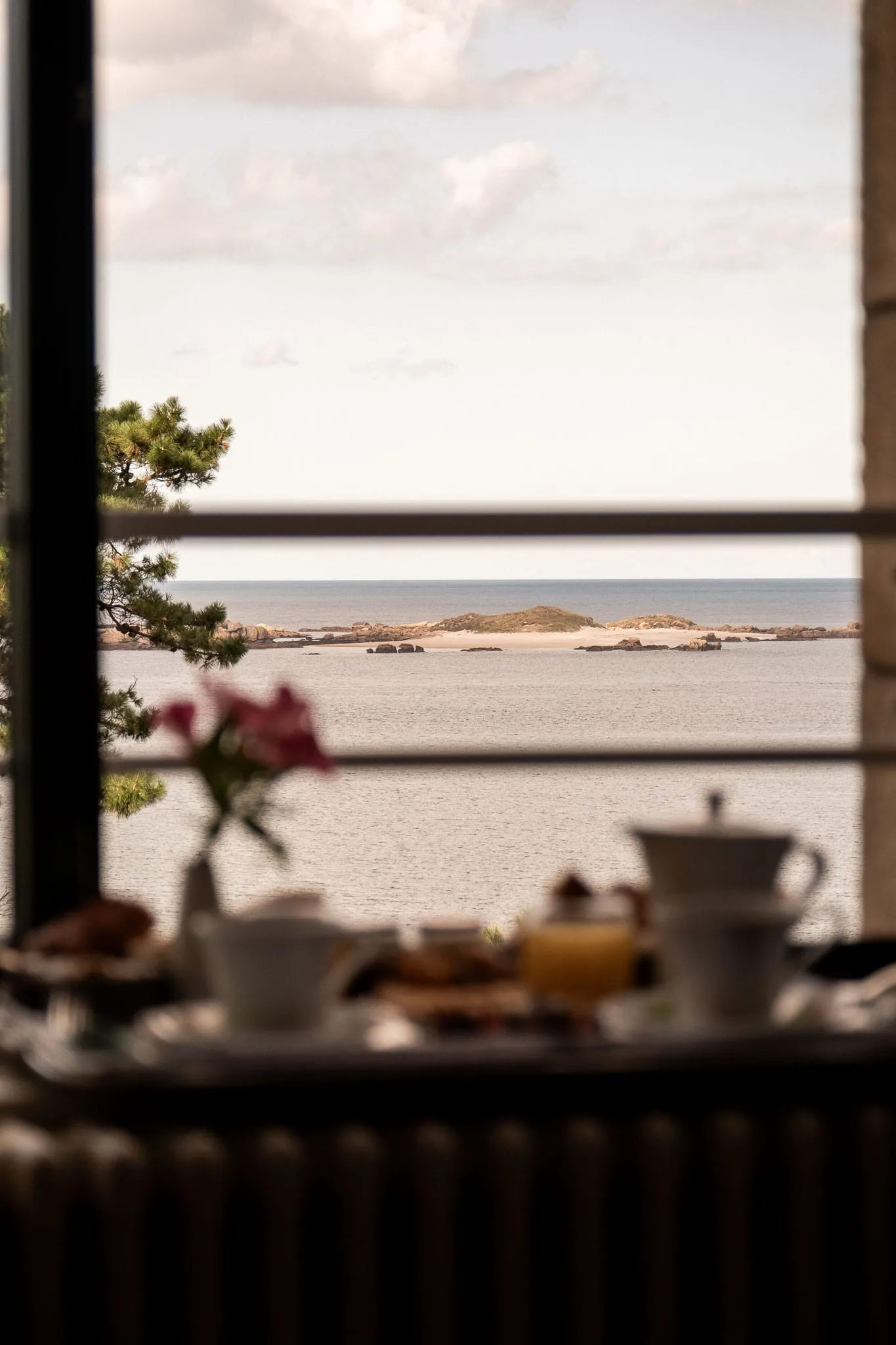 Petit-déjeuner dressé devant une fenêtre ouverte sur la mer
