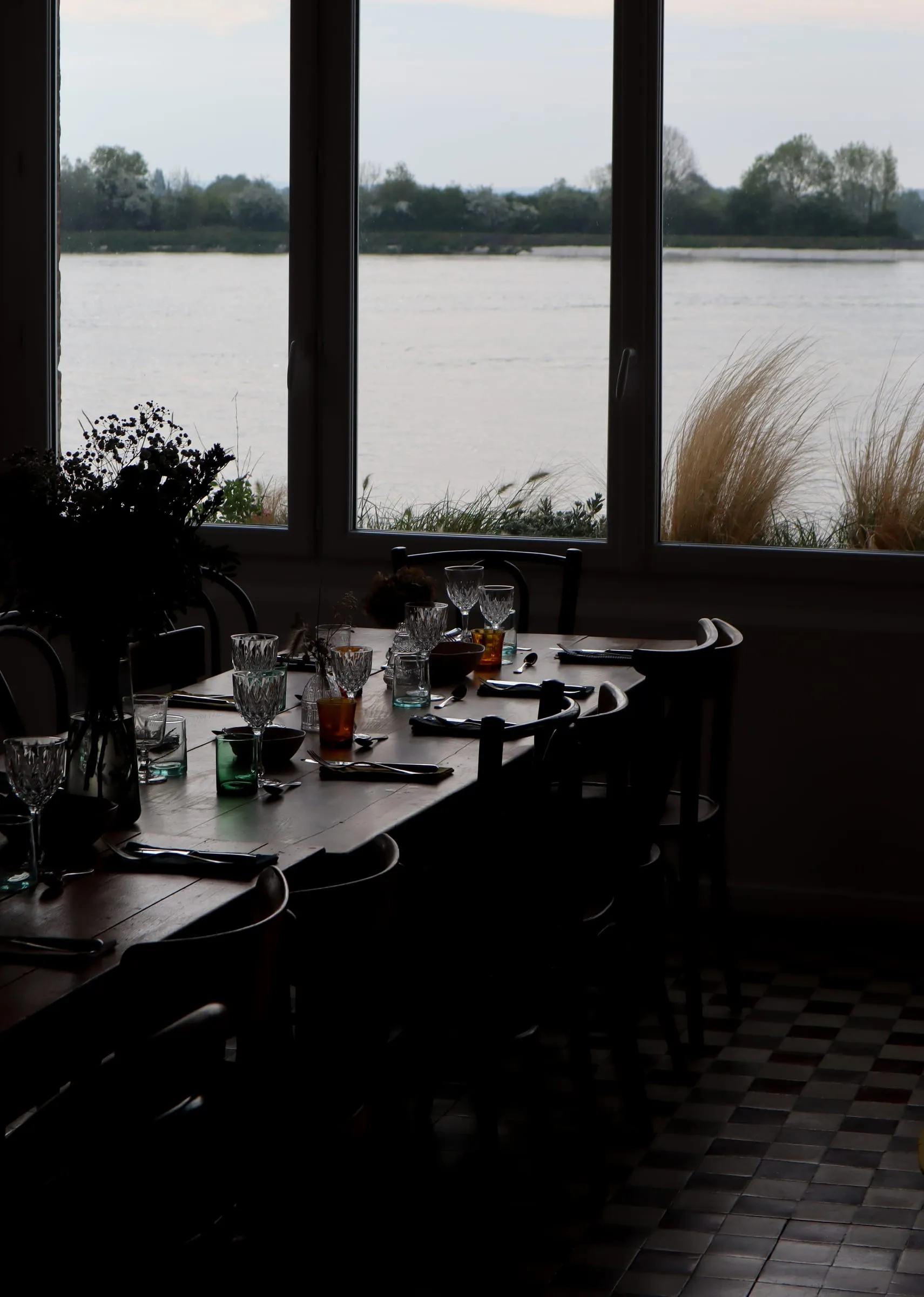 Longue table dressée devant les fenêtres ouvertes sur la Seine, à La Maison Plume